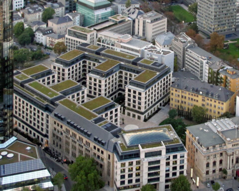 Luftaufnahme eines modernen Gebäudekomplexes mit begrünten Dächern; am unteren Bildrand ist ein Crédit-Agricole-Gebäude zu sehen.