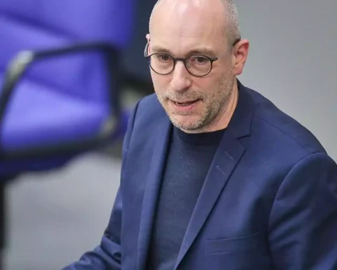 Mann mit Brille in blauem Sakko in einem Innenraum.