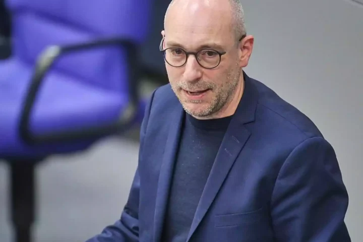 Mann mit Brille in blauem Sakko in einem Innenraum.