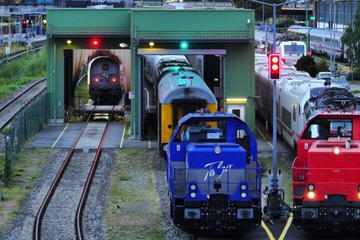 Mehrere Lokomotiven stehen in einem Bahndepot vor einer Waschanlage und auf Gleisen.