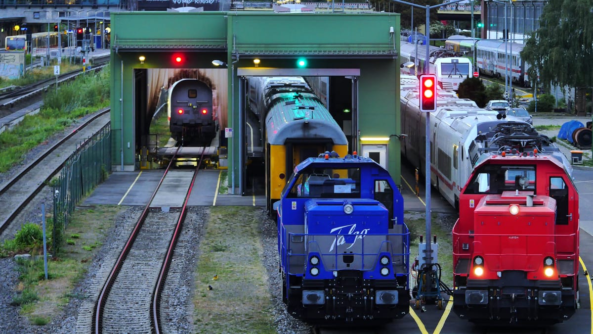 Mehrere Lokomotiven stehen in einem Bahndepot vor einer Waschanlage und auf Gleisen.