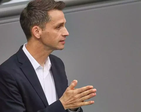 Andreas Audretsch im dunklen Anzug bei einer politischen Veranstaltung, im Profil und mit gefalteten Händen.