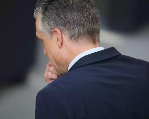 Ein Mann im dunklen Anzug von hinten gesehen, die Hand am Kinn.