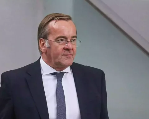 Boris Pistorius im dunklen Anzug und mit Krawatte vor neutralem Hintergrund.