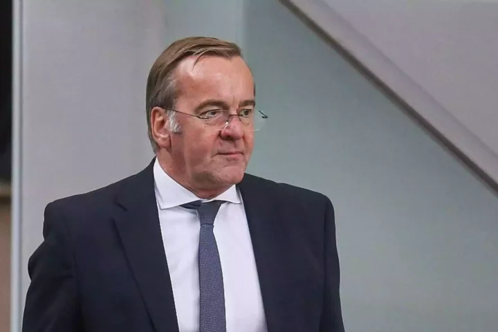 Boris Pistorius im dunklen Anzug und mit Krawatte vor neutralem Hintergrund.