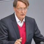 Friedrich Merz spricht an einem Redepult vor grauem Hintergrund.