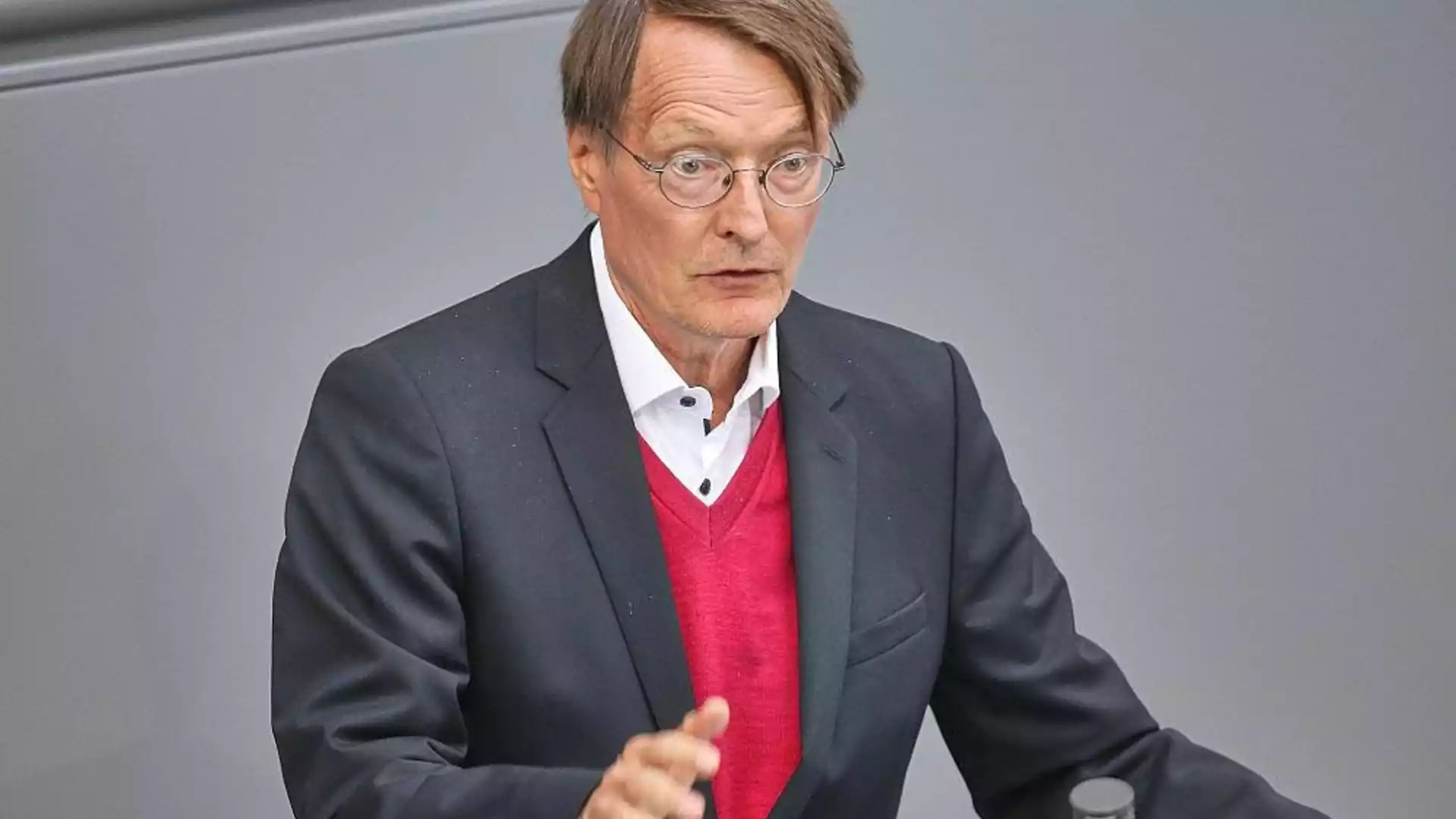 Friedrich Merz spricht an einem Redepult vor grauem Hintergrund.