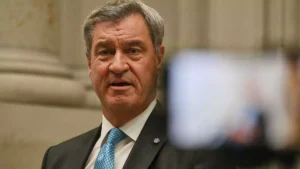 Markus Söder spricht in einem Innenraum vor einer Kamera.