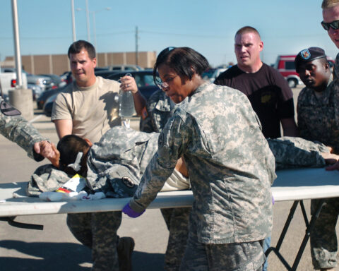 US-Soldaten und Sanitäter versorgen eine liegende Person neben einem Klapptisch auf einem Parkplatz.