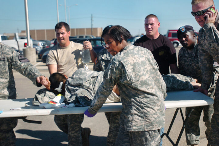 US-Soldaten und Sanitäter versorgen eine liegende Person neben einem Klapptisch auf einem Parkplatz.