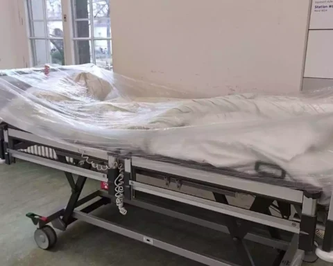 Ein mit Folie abgedecktes Krankenhausbett steht auf einem Stationsflur.
