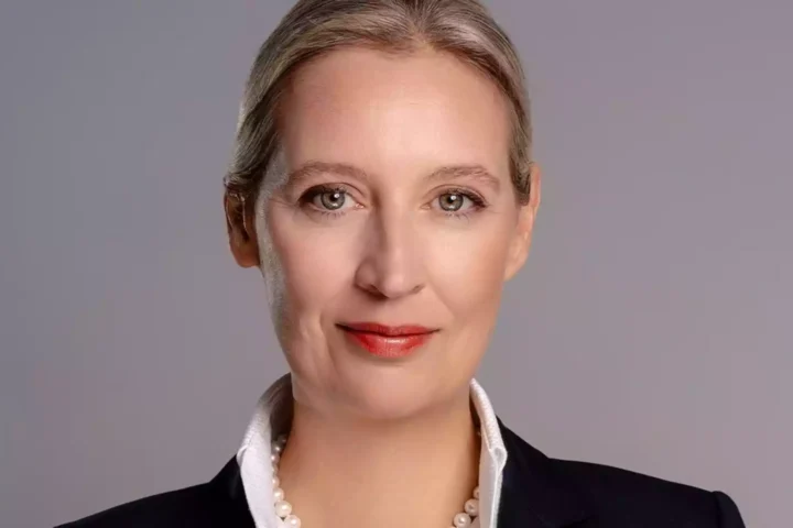 Porträt von Alice Weidel vor grauem Hintergrund.