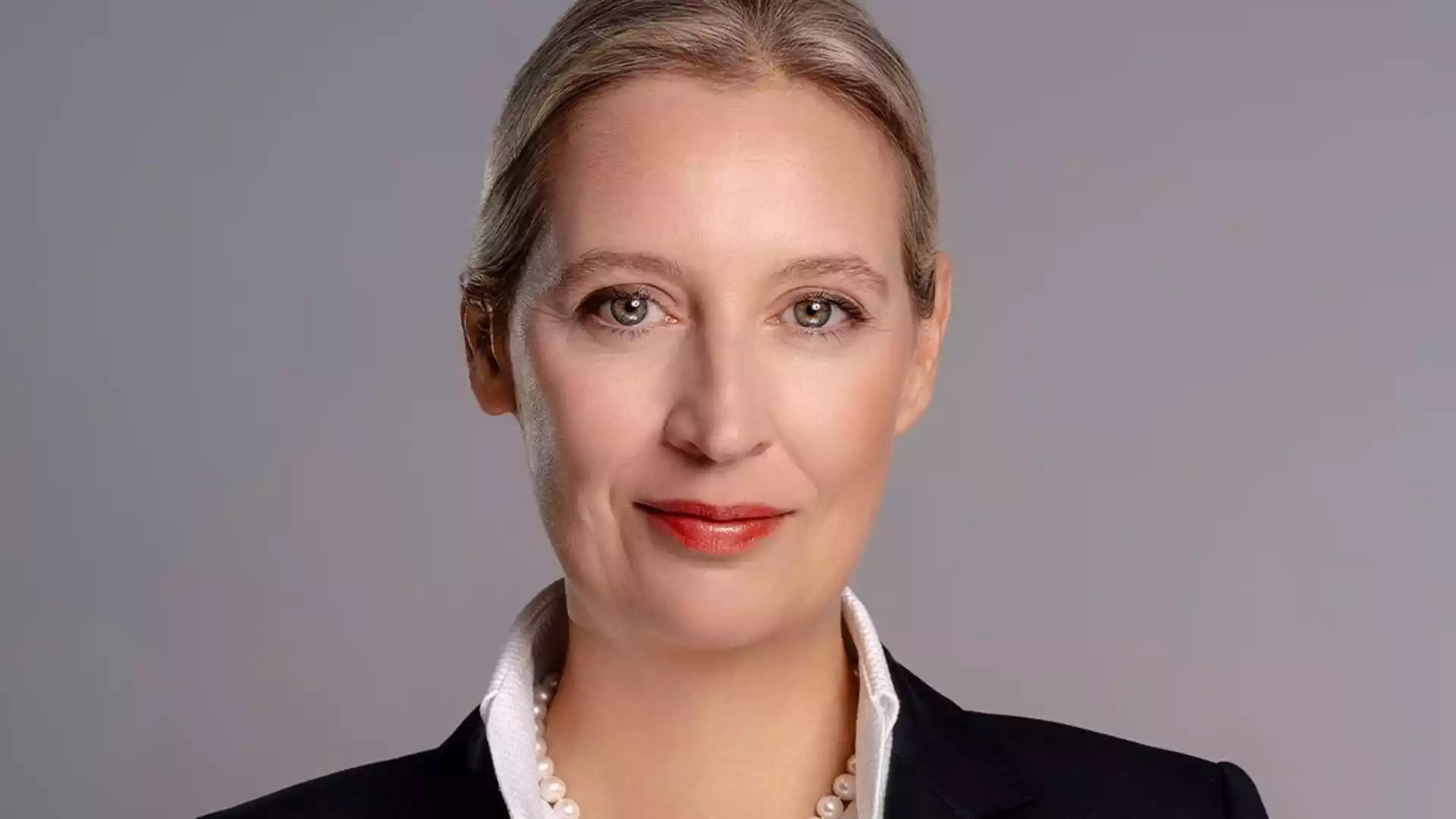 Porträt von Alice Weidel vor grauem Hintergrund.