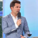 Steffen Krach spricht in einem Fernsehstudio in ein Mikrofon.