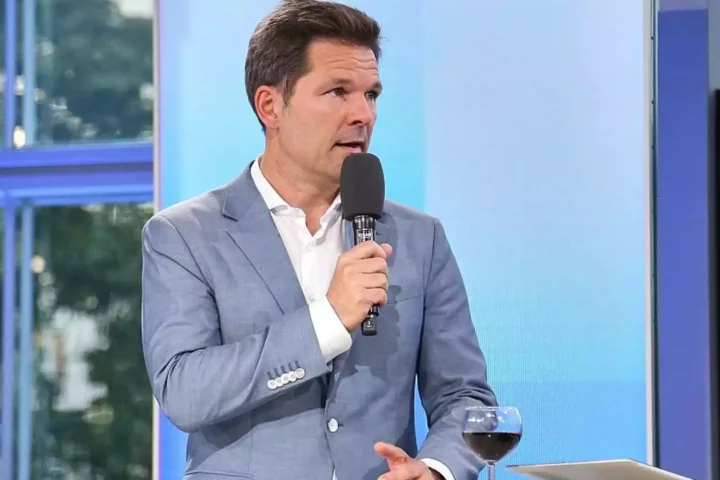 Steffen Krach spricht in einem Fernsehstudio in ein Mikrofon.