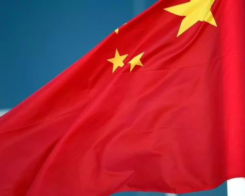Chinesische Flagge weht vor blauem Hintergrund.