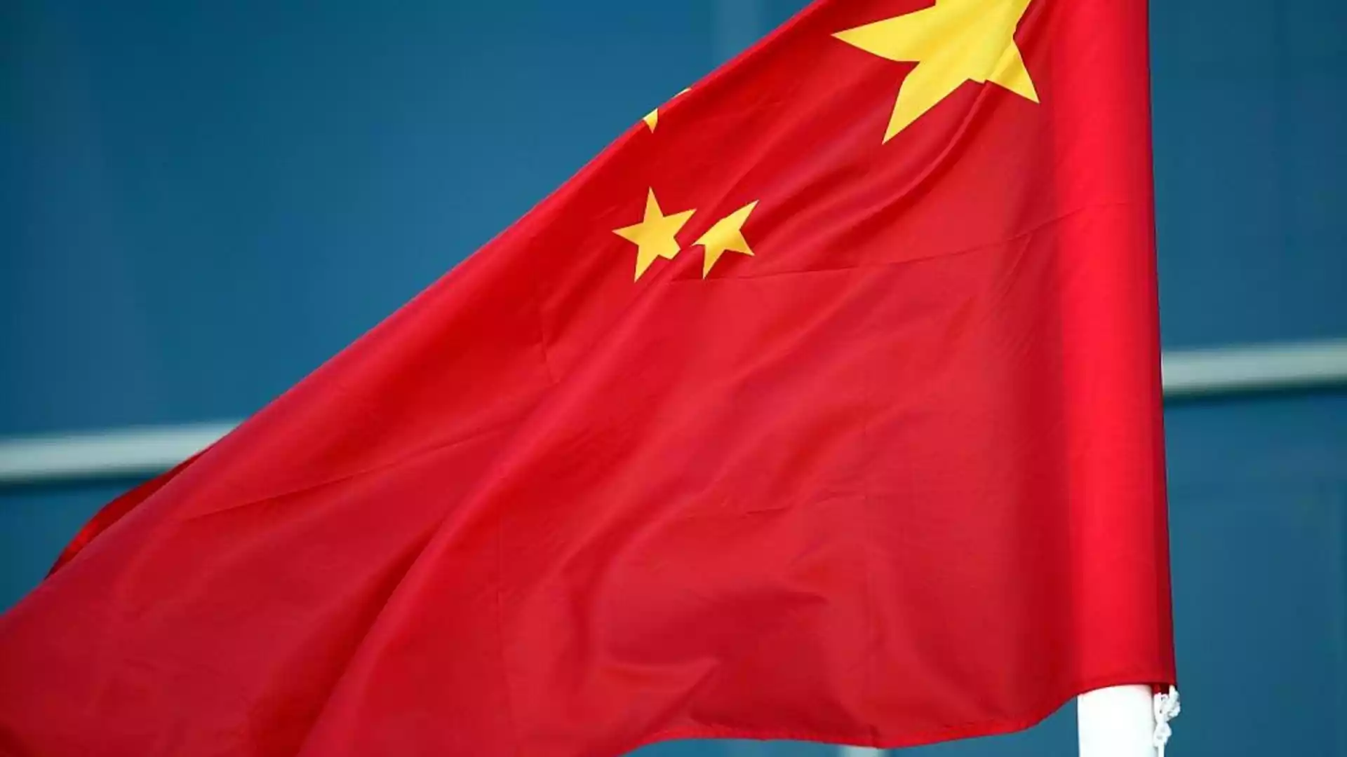 Chinesische Flagge weht vor blauem Hintergrund.