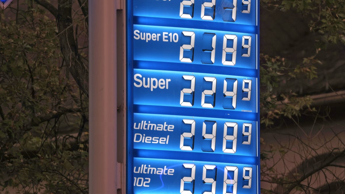 Beleuchtete Preistafel einer Tankstelle mit Benzin- und Dieselpreisen bei Nacht.
