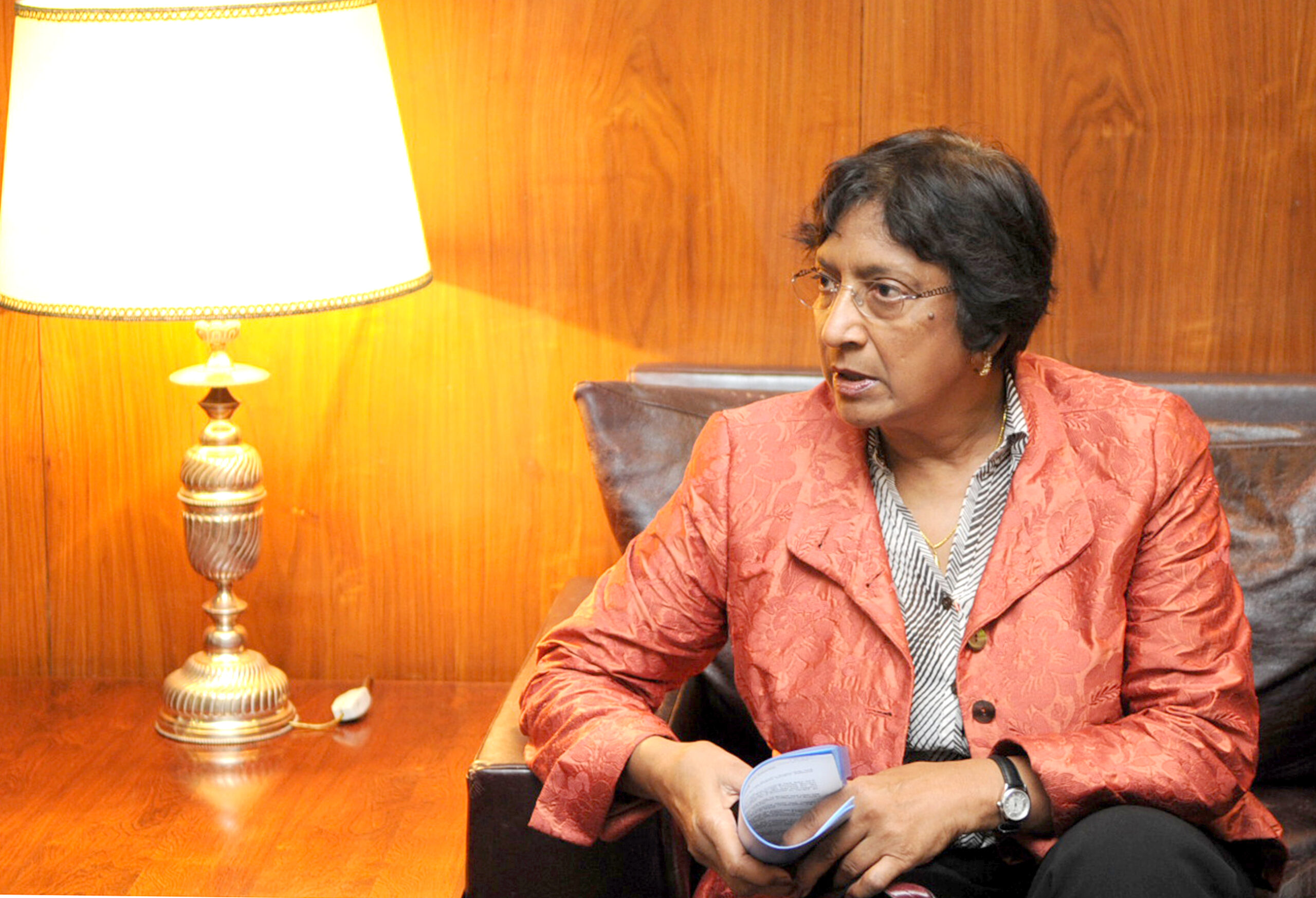 Navanethem Pillay sitzt in einem Sessel und hält Unterlagen in den Händen.