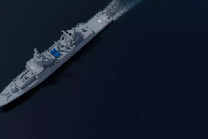 Luftansicht einer grauen Fregatte auf dunkler See mit sichtbaren Aufbauten und Decksbereichen.
