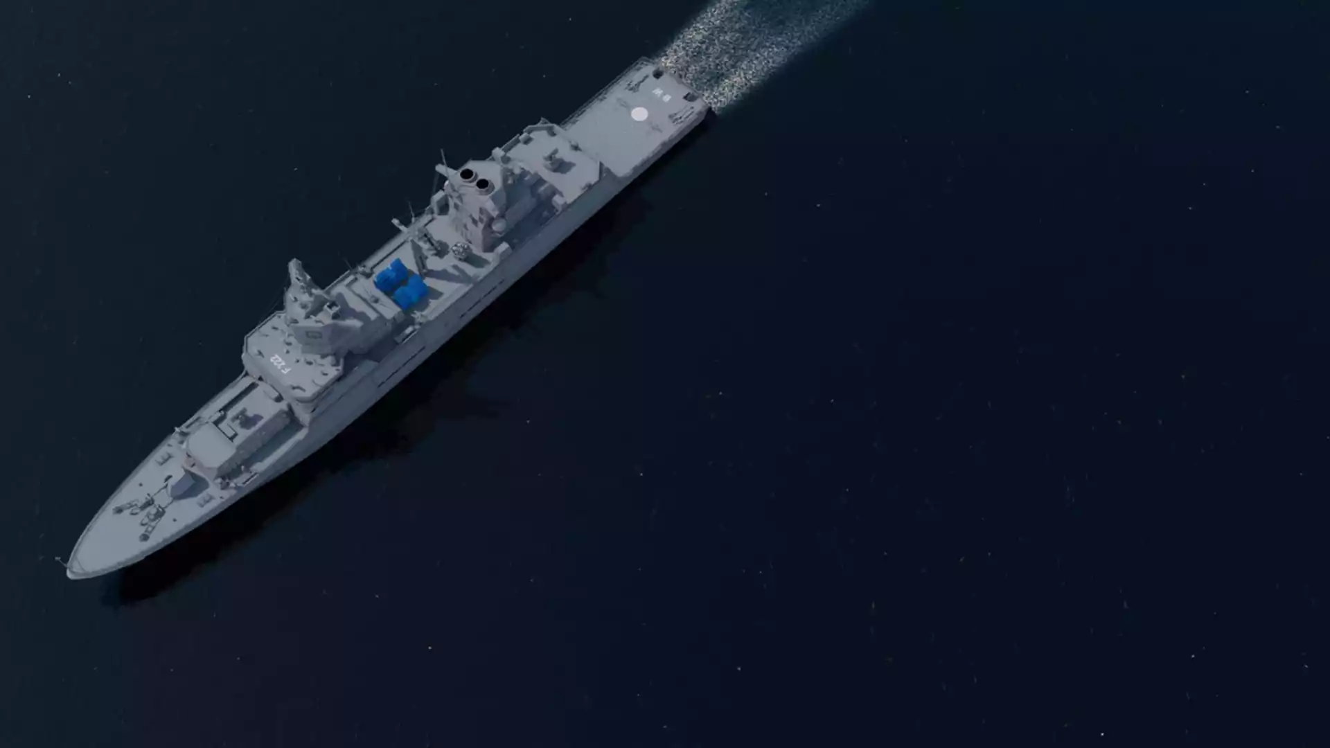 Luftansicht einer grauen Fregatte auf dunkler See mit sichtbaren Aufbauten und Decksbereichen.
