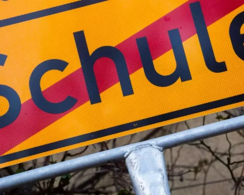 Nahaufnahme eines gelben Schulwegweisers mit dem Wort „Schule“.