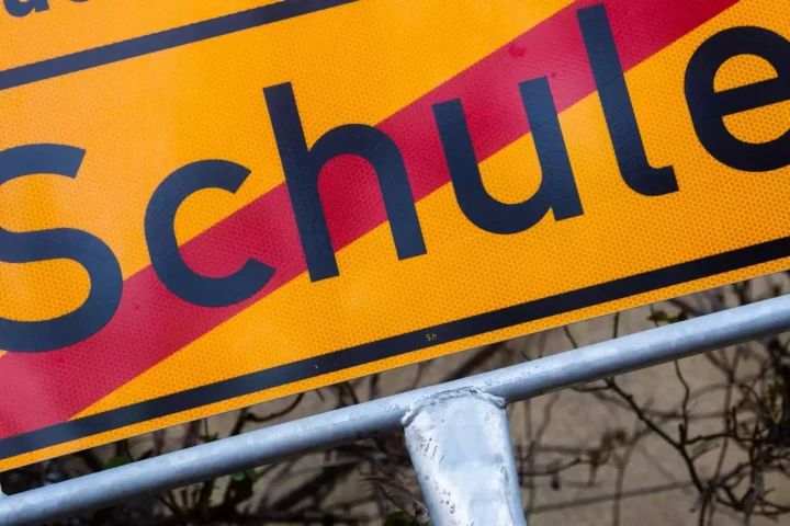 Nahaufnahme eines gelben Schulwegweisers mit dem Wort „Schule“.