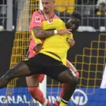 Zwei Fußballspieler im Zweikampf vor dem Tor, einer im gelben Trikot von Borussia Dortmund.