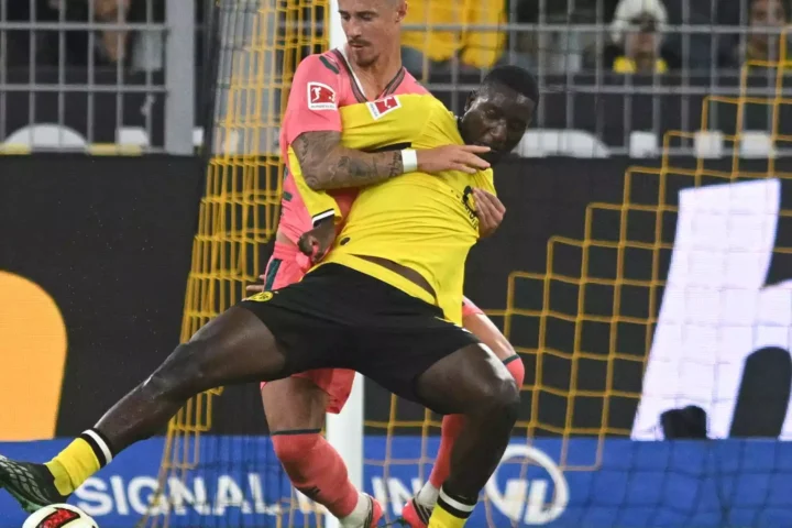 Zwei Fußballspieler im Zweikampf vor dem Tor, einer im gelben Trikot von Borussia Dortmund.