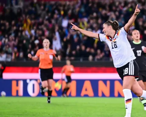 Eine deutsche Fußballerin in weißem Trikot jubelt mit ausgebreiteten Armen vor dem Publikum.
