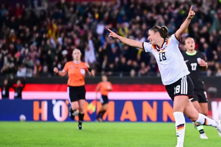 Eine deutsche Fußballerin in weißem Trikot jubelt mit ausgebreiteten Armen vor dem Publikum.