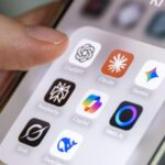 Hand hält ein Smartphone mit mehreren KI-App-Symbolen auf dem Bildschirm.