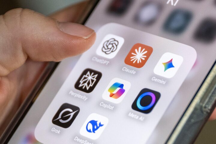 Hand hält ein Smartphone mit mehreren KI-App-Symbolen auf dem Bildschirm.