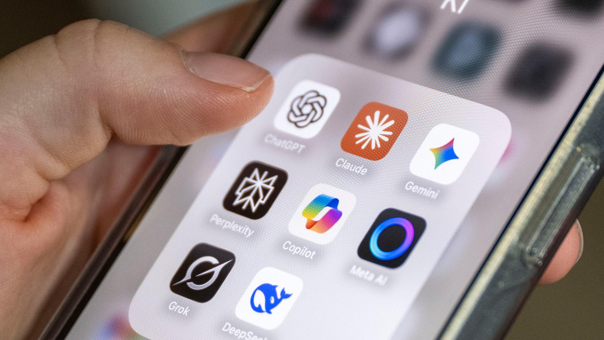 Hand hält ein Smartphone mit mehreren KI-App-Symbolen auf dem Bildschirm.