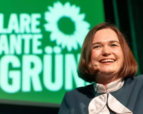 Eine Frau spricht mit Headset-Mikrofon vor einem grünen Hintergrund mit Grünen-Logo und dem Schriftzug „KlaRe Kante GRÜN“.