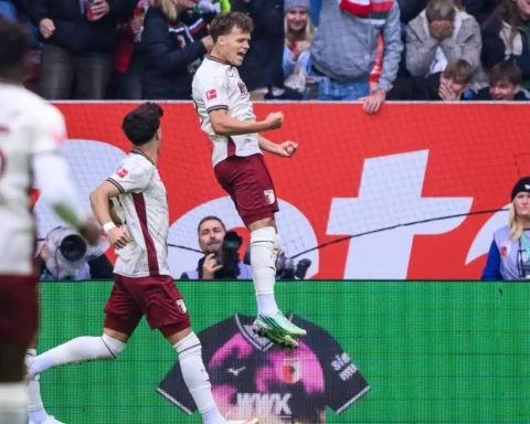 FC-Augsburg-Spieler jubeln nach einem Treffer vor den Fans im Stadion.