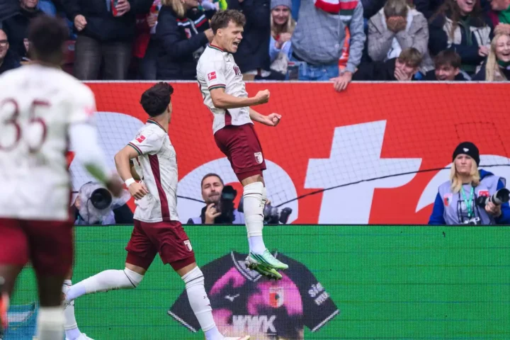 FC-Augsburg-Spieler jubeln nach einem Treffer vor den Fans im Stadion.