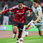 Zwei Fußballspieler von 1. FC Nürnberg und VfL Wolfsburg kämpfen am Ball auf dem Spielfeld.