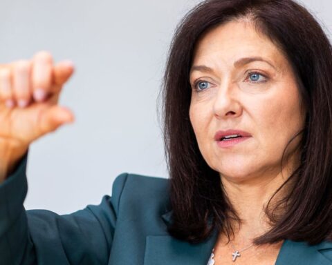 Katherina Reiche spricht vor hellem Hintergrund und hebt eine Hand.