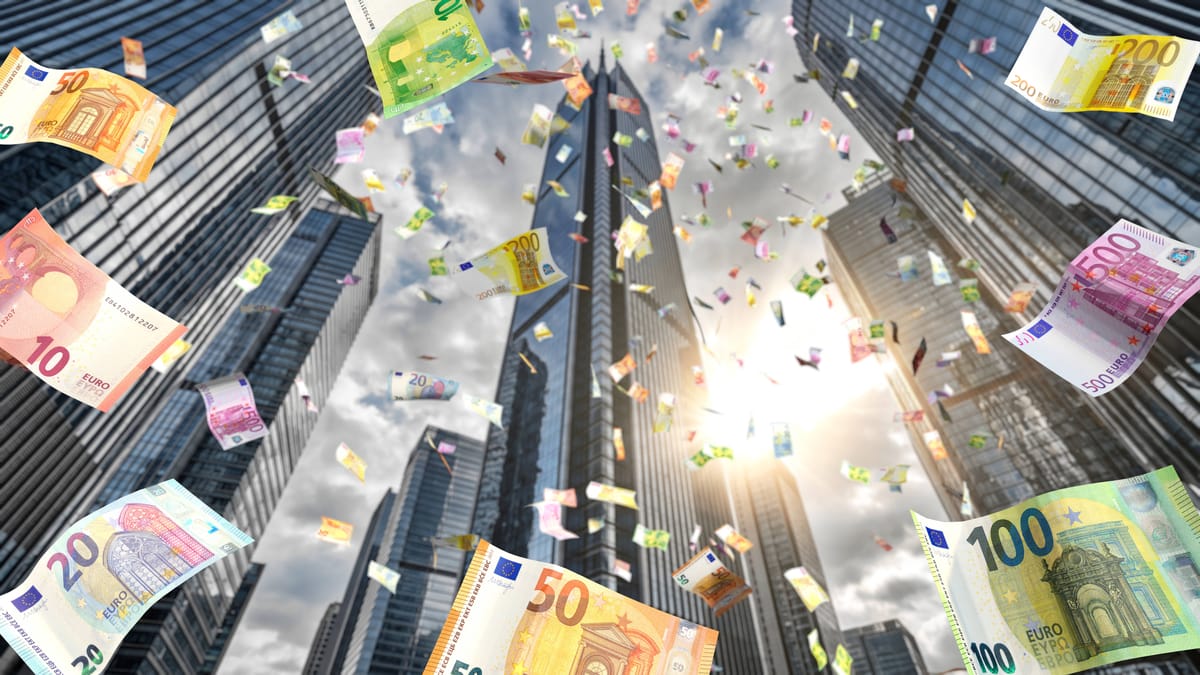 Drei ETFs sollen monatliche Ausschüttungen ermöglichen 1 Euro-Banknoten schweben vor modernen Hochhäusern in einer Finanzszene.