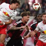 Spieler von RB Leipzig und Eintracht Frankfurt kämpfen im Kopfballduell um den Ball.