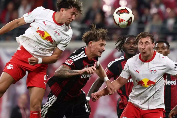 Spieler von RB Leipzig und Eintracht Frankfurt kämpfen im Kopfballduell um den Ball.