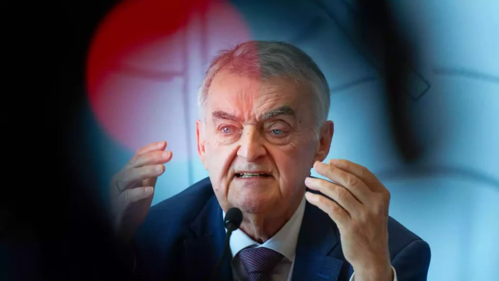 Herbert Reul spricht an einem Mikrofon und gestikuliert mit beiden Händen.