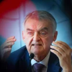 Herbert Reul spricht an einem Mikrofon und gestikuliert mit beiden Händen.