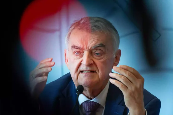 Herbert Reul spricht an einem Mikrofon und gestikuliert mit beiden Händen.