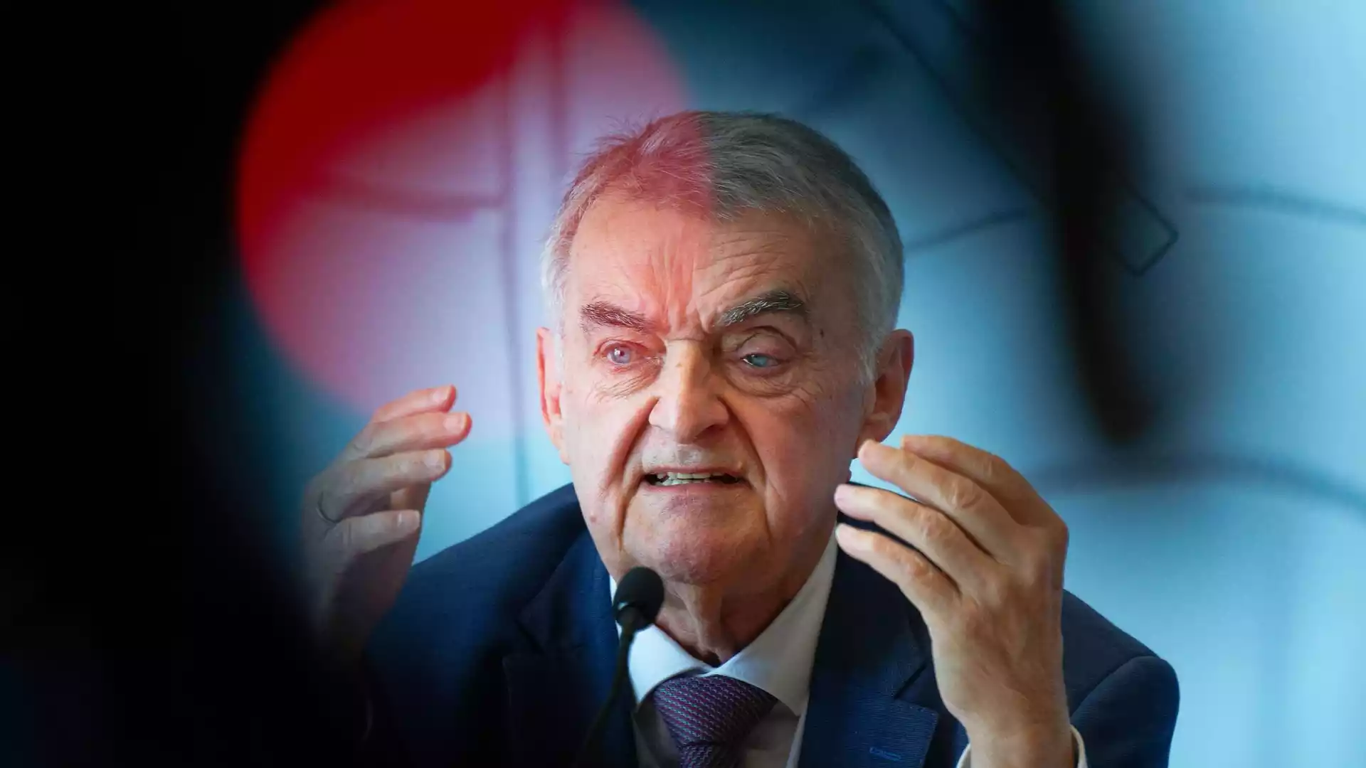 Herbert Reul spricht an einem Mikrofon und gestikuliert mit beiden Händen.
