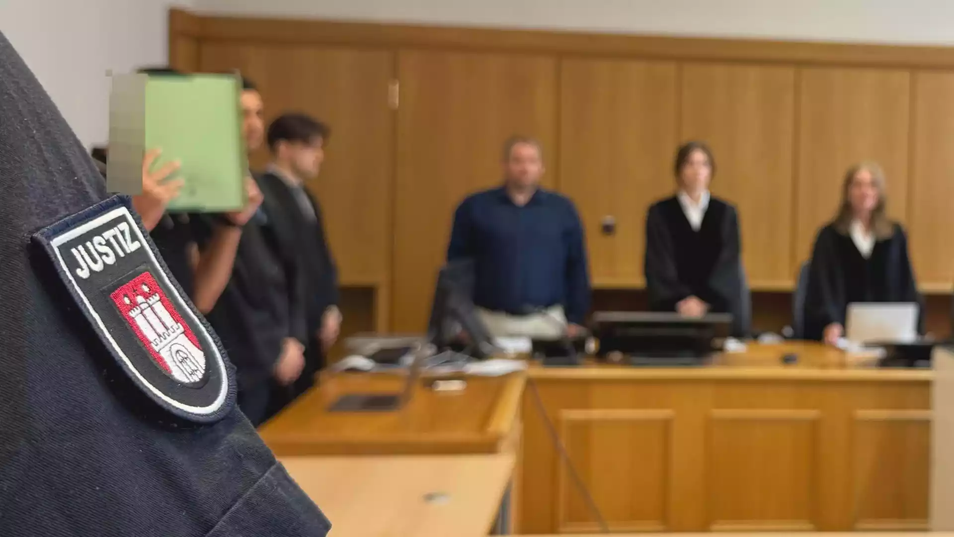 Bundesjustizministerium verschärft Regeln für Schöffen und ehrenamtliche Richter 1 Nahaufnahme einer Justiz-Uniform mit Abzeichen vor einer Gerichtsszene im Hintergrund.