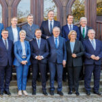 Mehrere Politikerinnen und Politiker posieren vor einem Gebäude für ein Gruppenfoto.