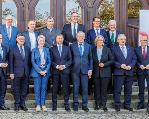 Mehrere Politikerinnen und Politiker posieren vor einem Gebäude für ein Gruppenfoto.