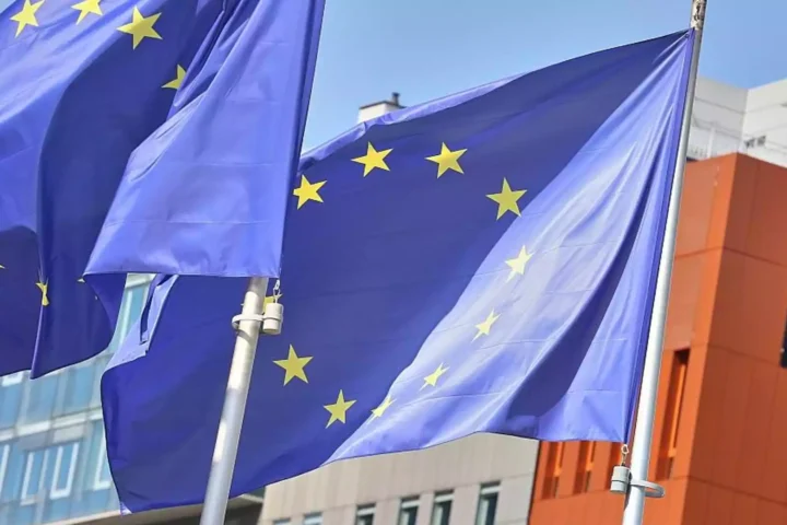 EU-Flaggen vor einem modernen Gebäude im Wind.